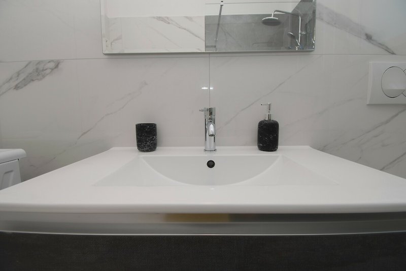 Ein modernes Badezimmer mit Spiegel, Armaturen und Waschbecken.