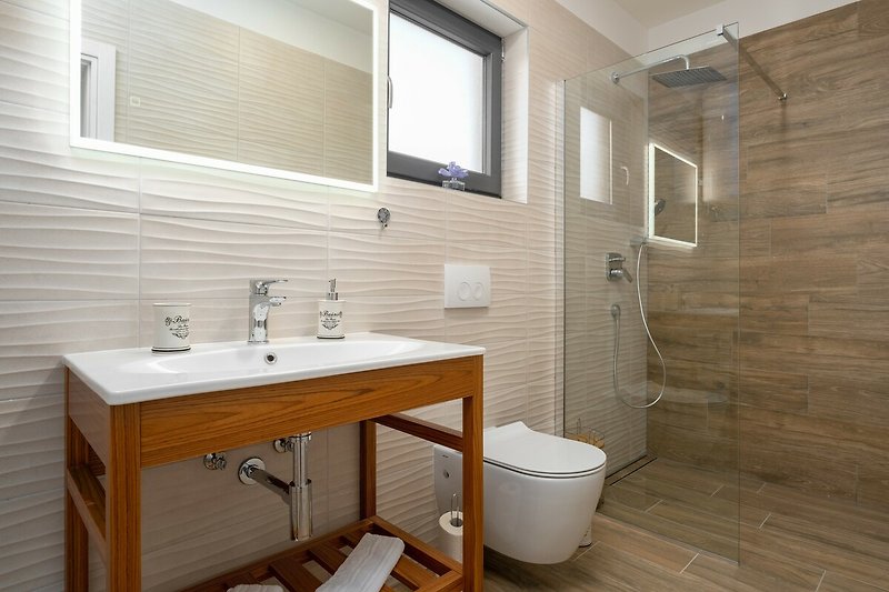 Modernes Badezimmer mit lila Akzenten, Spiegel, Waschbecken und Fenster.