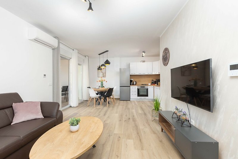 Wohnzimmer mit Holzmöbeln, Couch, Pflanze und Bilderrahmen.