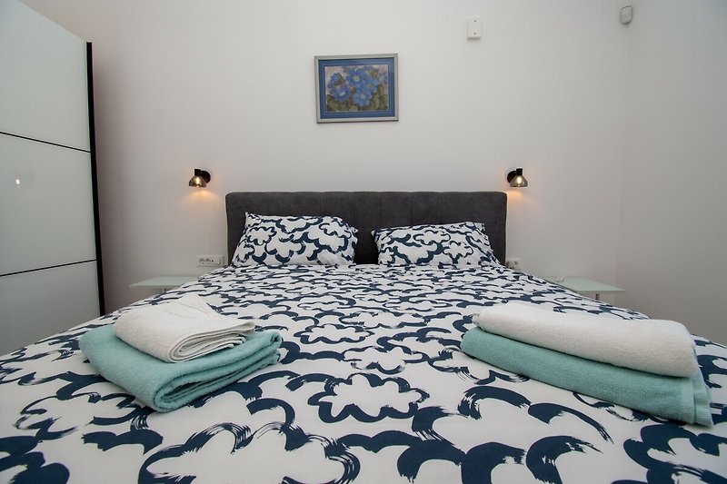 Gemütliches Schlafzimmer mit Holzbett und blauem Fenster.