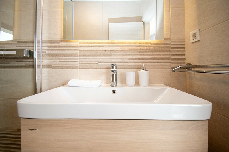 Badezimmer mit Spiegel, Waschbecken und Holzschrank.