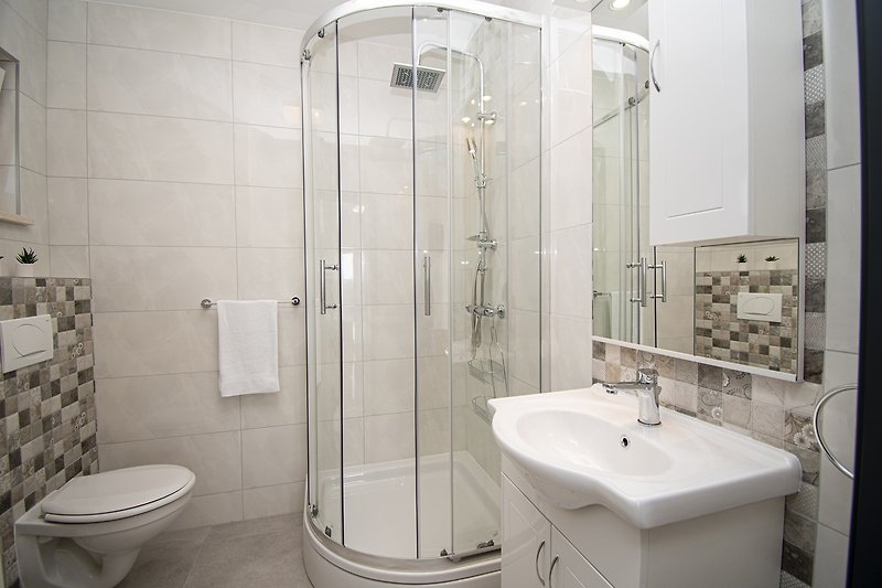 Schwarze Dusche mit Spiegel, Waschbecken und lila Armaturen.