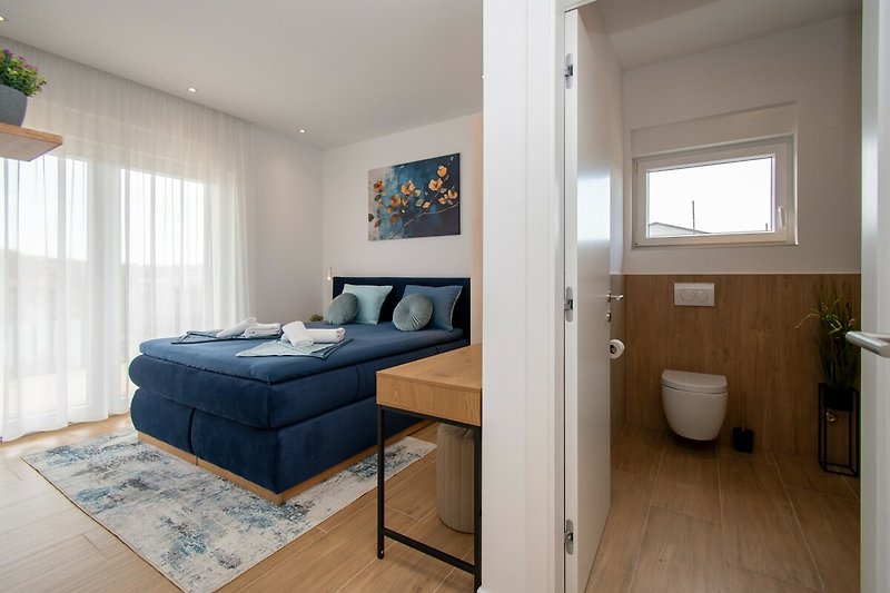 Modernes Schlafzimmer mit stilvollem Bett, gemütlicher Einrichtung und dekorativen Kissen.
