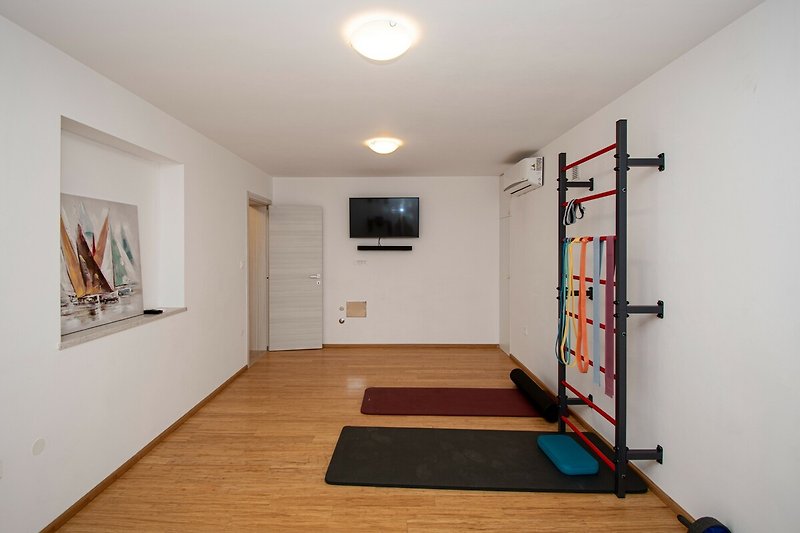 Geräumiger Raum mit Holzboden, Türen und Deckenbeleuchtung.