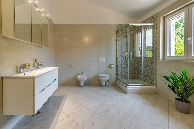 Moderne Badezimmer mit Holzboden, Fliesen und Pflanzen.