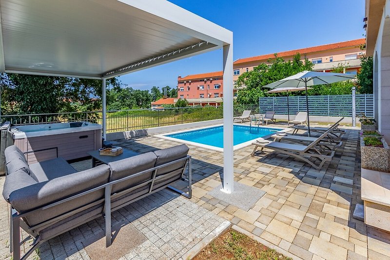 Schwimmbad mit Sonnenliegen und Außenmöbeln in einem modernen Haus.