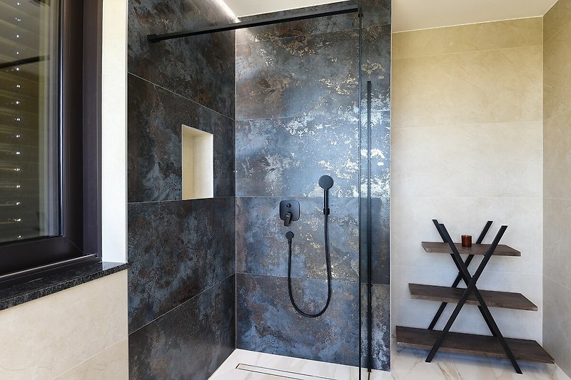 Ein stilvolles Badezimmer mit Holzboden, modernen Armaturen und einer gläsernen Duschtür.