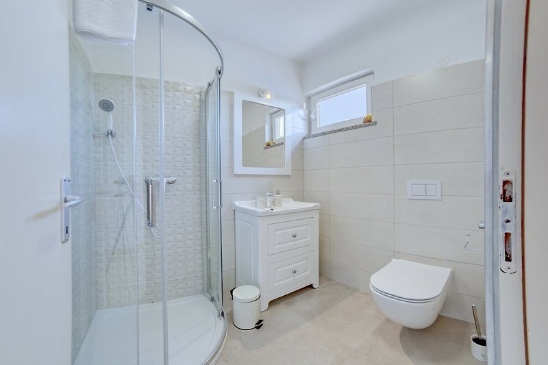Modernes Badezimmer mit lila Akzenten und Glasdusche.