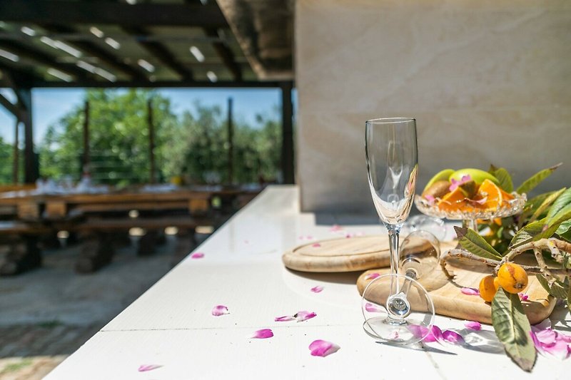 Ein stilvolles Tischarrangement mit Geschirr, Gläsern und Blumen im Freien.
