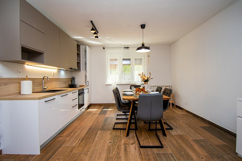 Moderne Küche mit Holzmöbeln, Beleuchtung und Küchengeräten.