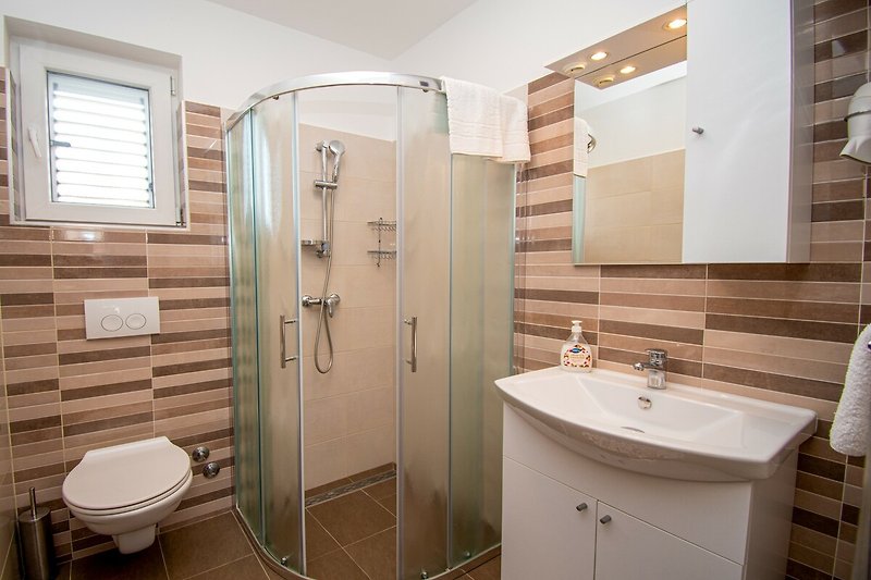 Genießen Sie die stilvolle Badezimmereinrichtung mit lila Waschbecken und Dusche. Entspannen Sie und erfrischen Sie sich!