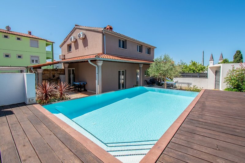 Elegante Villa mit Pool, Holzdetails und üppiger Landschaft.