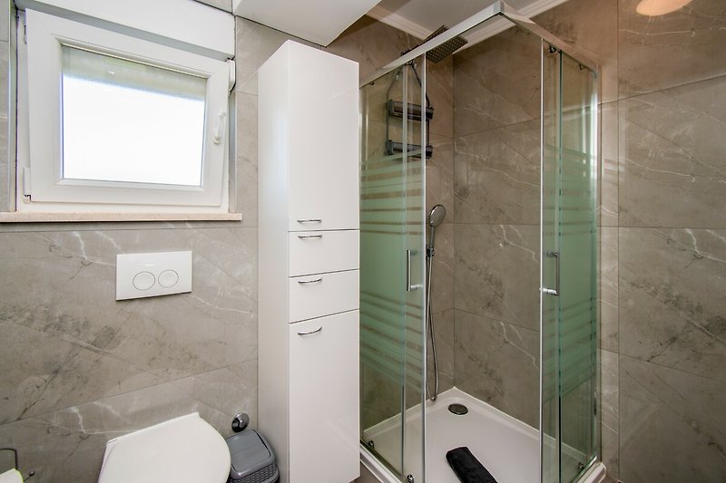 Modernes Badezimmer mit Dusche, Fenster, Glas und Aluminium.