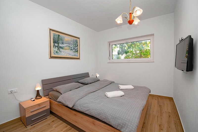 Gemütliches Schlafzimmer mit stilvollem Holzbett und gemusterter Bettwäsche.