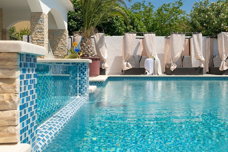 Schwimmbecken mit blauem Wasser und Palmen im Hintergrund.