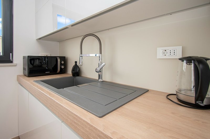 Moderne Küche mit Holzschrank, Spüle und Fenster.