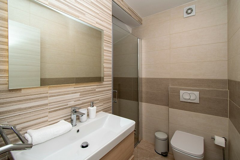 Modernes Badezimmer mit Spiegel, Waschbecken und Holzschrank.
