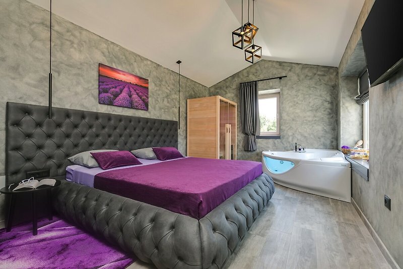 Gemütliches Schlafzimmer mit lila Bettwäsche und Holzmöbeln. Entspannen Sie sich in stilvollem Ambiente.