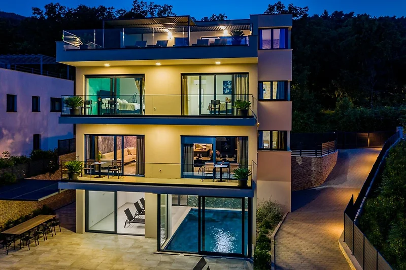 Moderne Wohnung mit Balkon, umgeben von Pflanzen und Abendbeleuchtung.