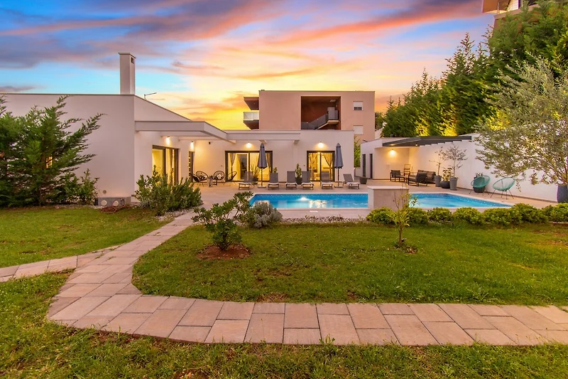 Villa mit Pool, gepflegter Bepflanzung und großzügigem Außenbereich.