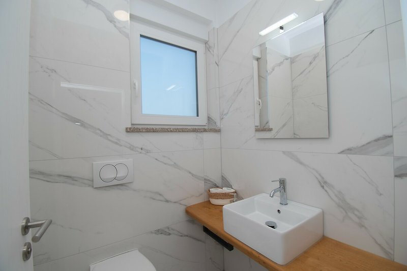 Badezimmer mit Spiegel, Waschbecken und Armaturen.