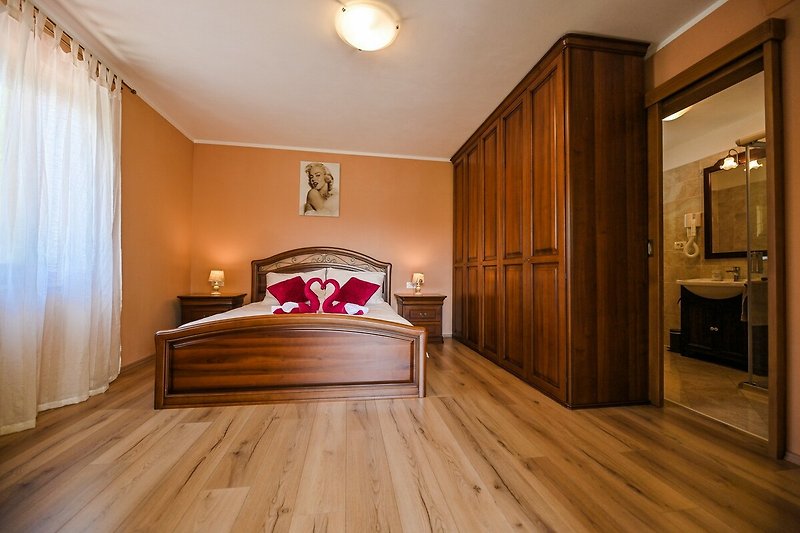 Schlafzimmer mit Holzmöbeln, Bett, Spiegel und Vorhängen - stilvoll eingerichtet!