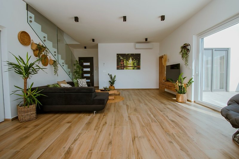 Wohnzimmer mit Pflanzen, Holz und gemütlicher Einrichtung.