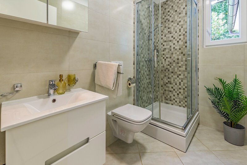 Badezimmer mit lila Vorhang, Spiegel, Waschbecken und Pflanze.