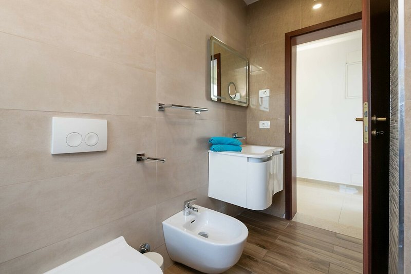 Badezimmer mit lila Waschbecken, Spiegel und Armatur.