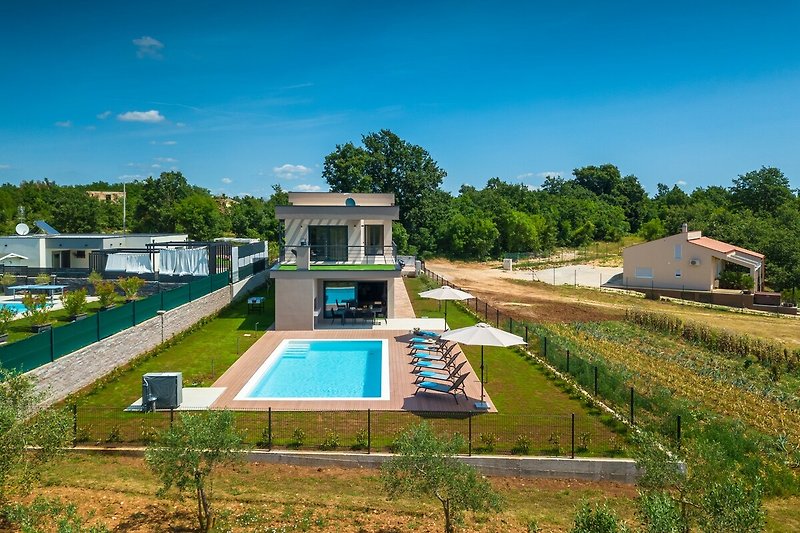 Schwimmbad mit grüner Landschaft und modernem Gebäude.