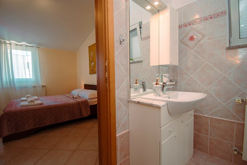 Gemütliches Badezimmer mit lila Vorhang, Holzmöbeln und Spiegel.
