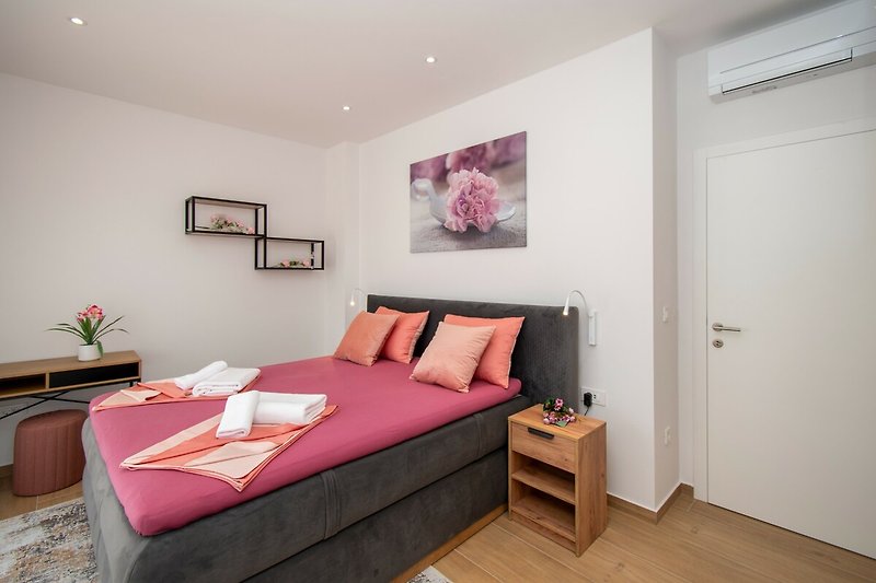 Moderne Schlafzimmer mit stilvollem Bett, dekorativen Kissen und Kunst. Gemütliche Atmosphäre.