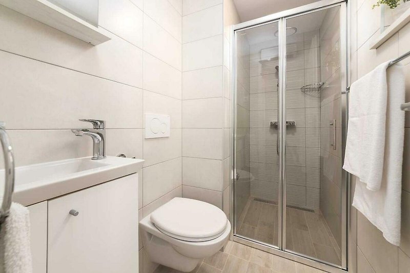 Modernes Badezimmer mit Glasdusche und elegantem Waschbecken.