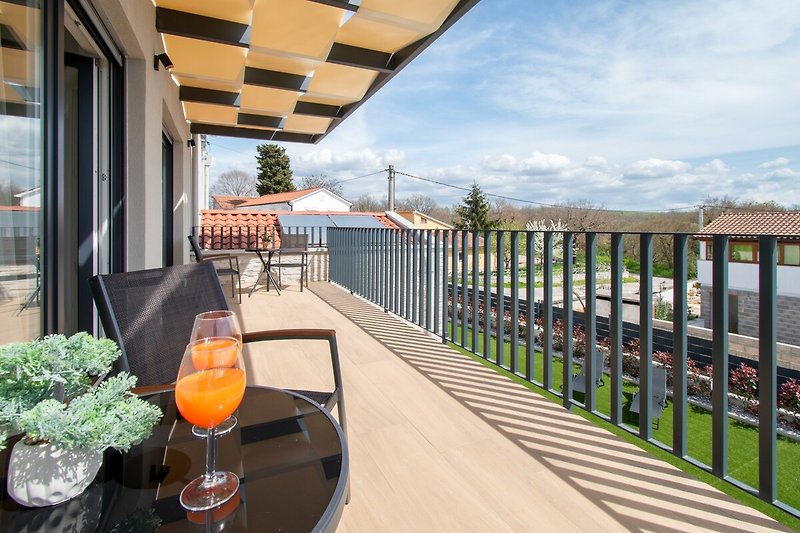 Sonnige Terrasse mit Tisch, Stühlen, Blumen und Glas - ideal für Entspannung!