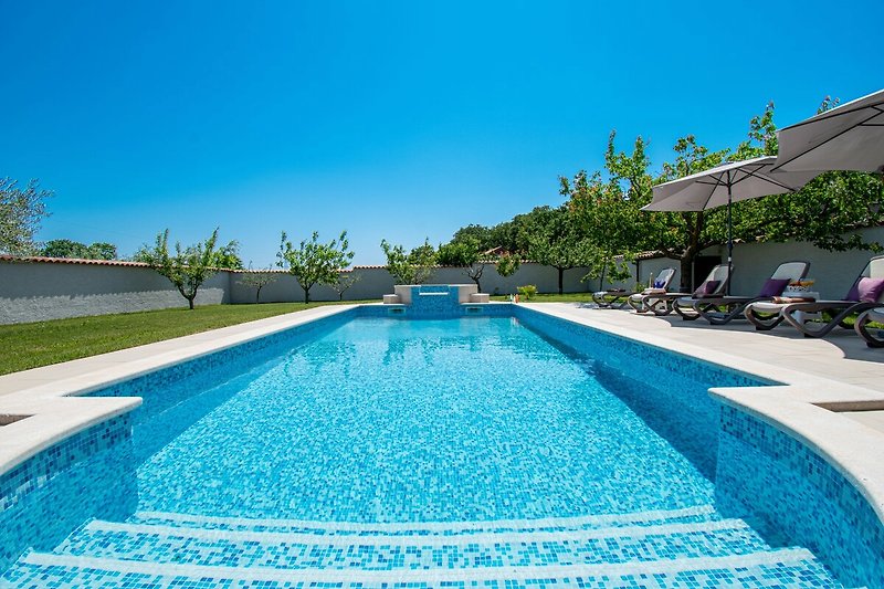 Entspannen Sie sich am Pool und genießen Sie das azurblaue Wasser unter dem sonnigen Himmel.