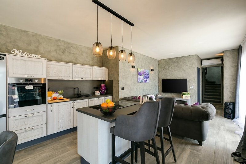 Schöne Küche mit Holzboden, grauen Schränken und modernen Geräten.