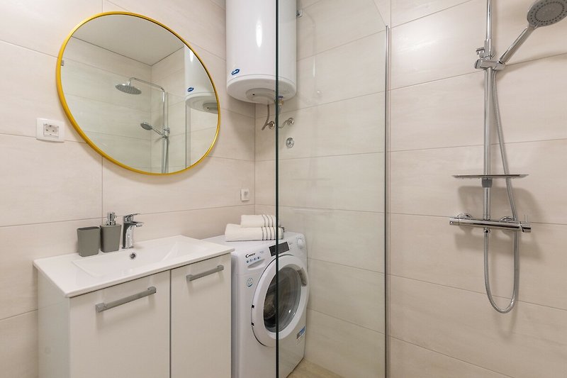 Modernes Badezimmer mit Dusche, Spiegel, Waschbecken und Armatur.