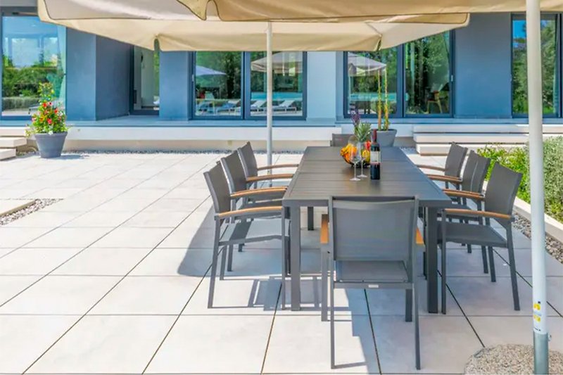 Geräumige Terrasse mit Tisch, Stühlen und Pflanzen.