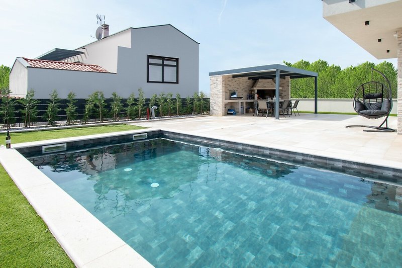 Luxuriöse Villa mit Pool, Palmen und modernem Design. Ideal für Entspannung und Erholung.
