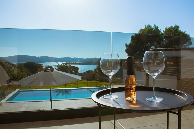 Schwimmbad mit Tisch, Stühlen, Wein- und Champagnergläsern.
