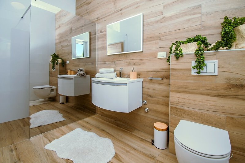 Moderne Badezimmerausstattung mit Keramik, Glas und Pflanzen - stilvoll eingerichtet.