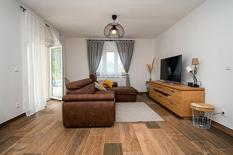 Wohnzimmer mit bequemen Möbeln, Pflanzen und Bilderrahmen.