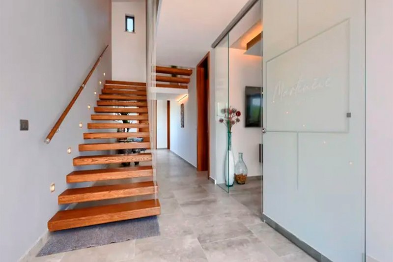 Eleganter Eingang mit Holztreppe und handgefertigtem Geländer.