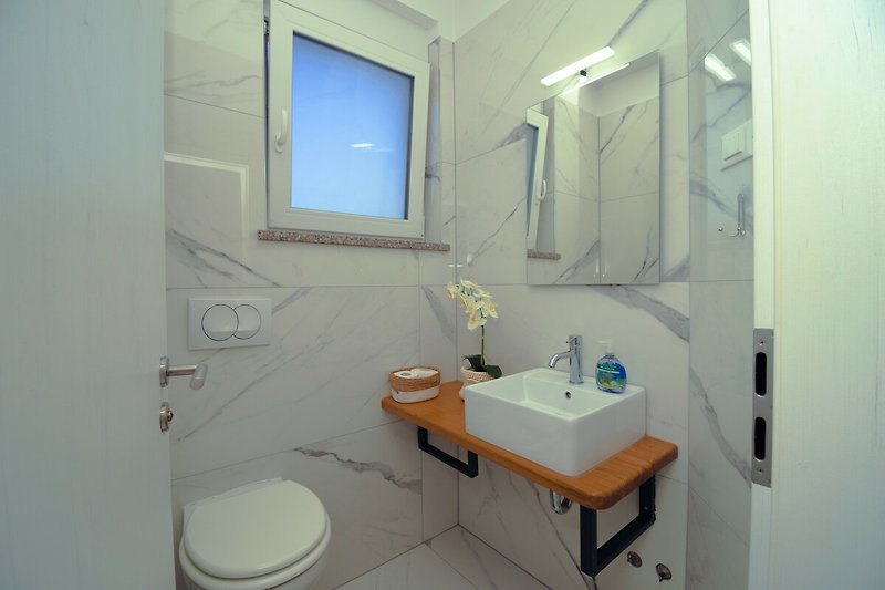 Schönes Badezimmer mit lila Wandfliesen und glänzenden Armaturen.