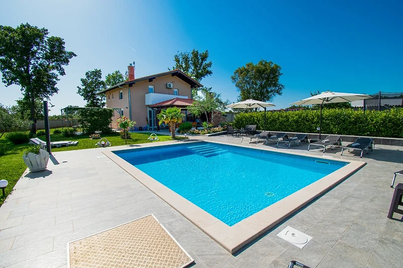 Schönes Haus mit Pool, umgeben von grüner Landschaft und Palmen.