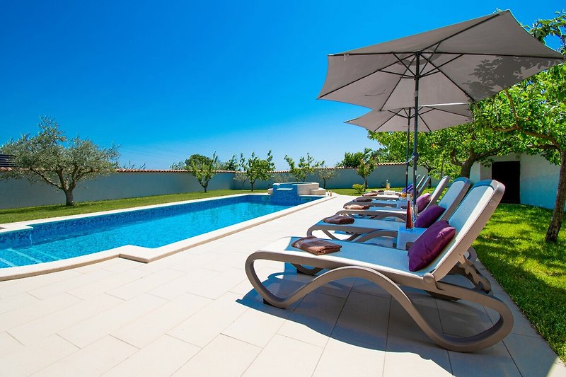 Entspannen Sie sich am Pool und genießen Sie die Aussicht auf das azurblaue Wasser und die umliegende Natur.