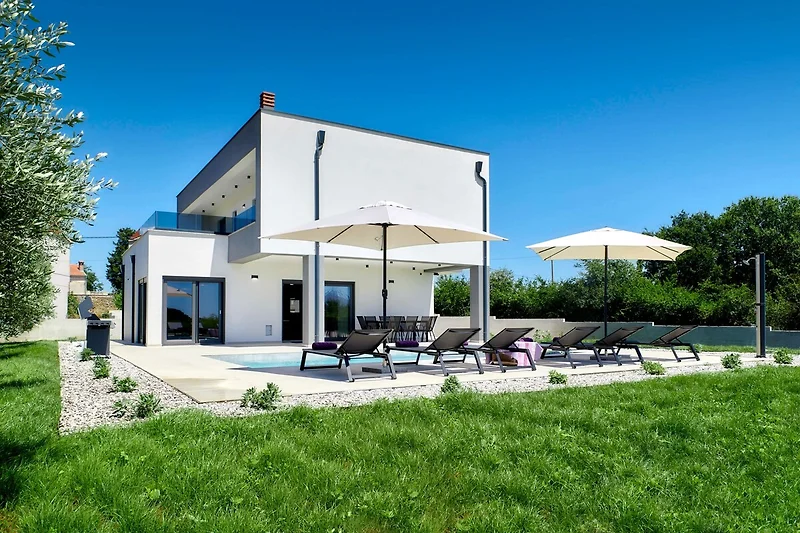 Auffahrt, Villa und gepflegte Gartenanlage mit besonderem Design.