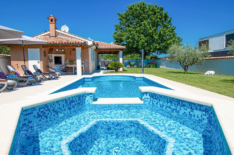 Entspannen Sie sich am Pool und genießen Sie die Aussicht auf das azurblaue Wasser und die grüne Landschaft.