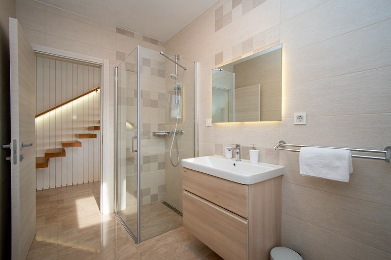 Modernes Badezimmer mit Spiegel, Waschbecken und Holzschrank.