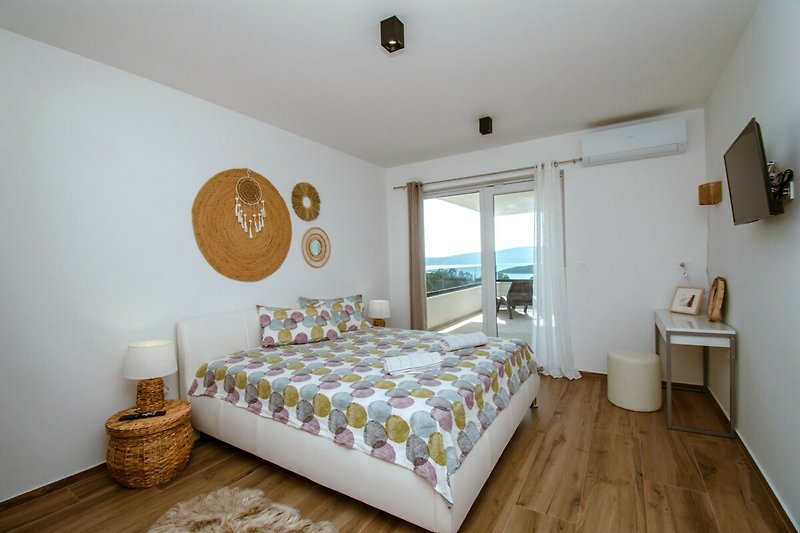 Wohnzimmer mit gemütlichem Bett, Holzmöbeln und Lampen.